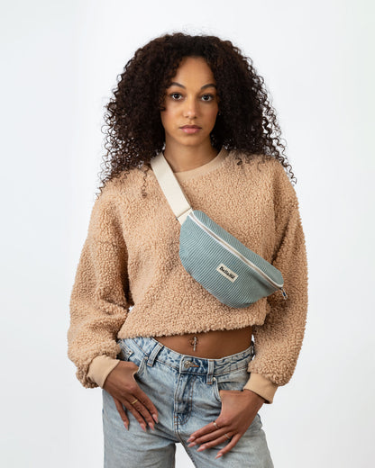 Sac Banane couleur gris/bleu (La célèste) portée par une femme sur fond blanc