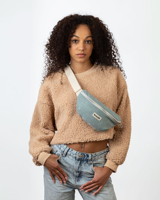Sac Banane couleur gris/bleu (La célèste) portée par une femme sur fond blanc