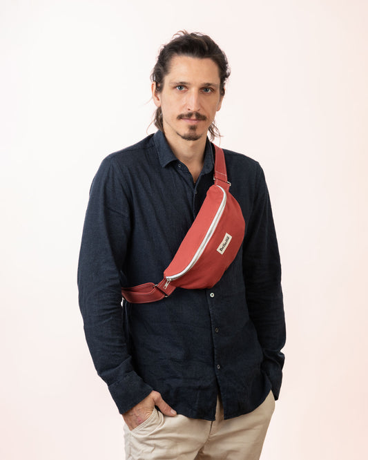 Sac Banane couleur rouge clair (La flamboyante) portée par un homme sur fond blanc