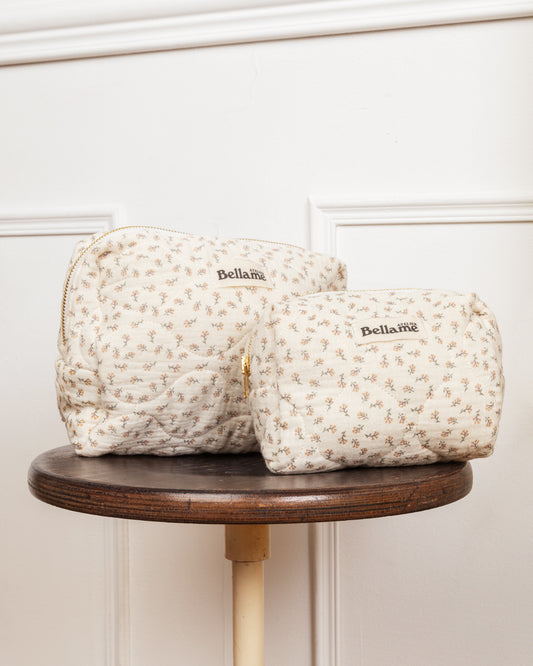 Une grande Trousse et une petite trousse claires et floraale posées sur une table ronde en bois